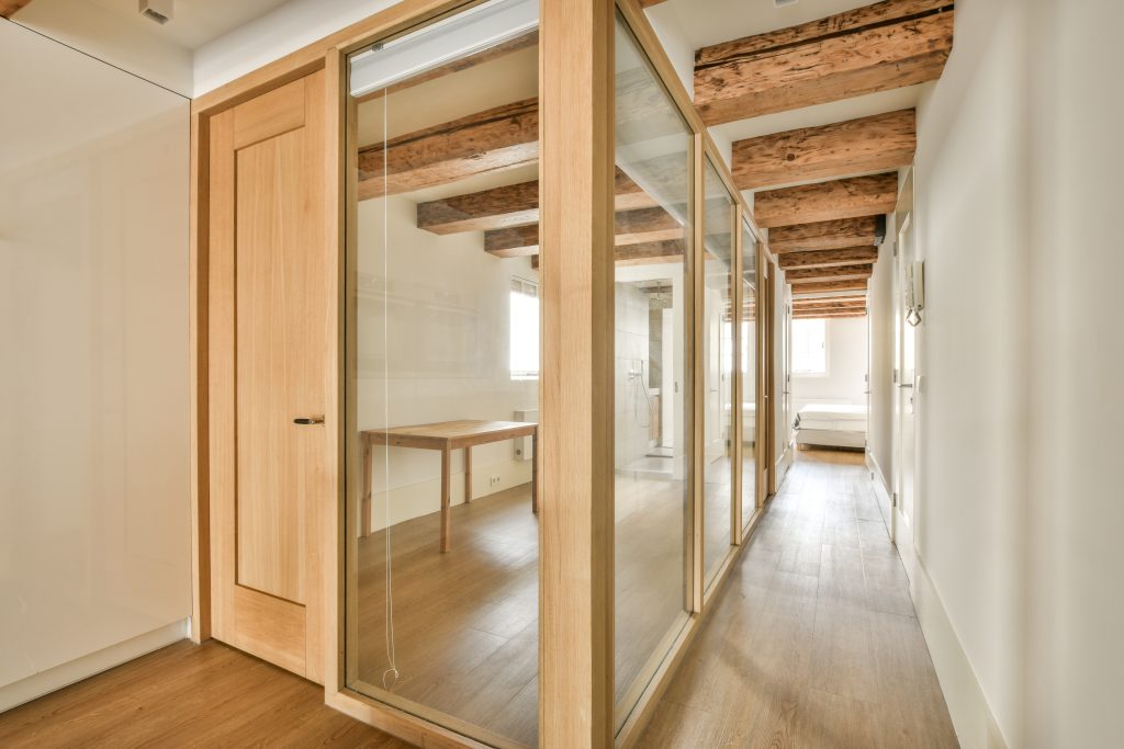 Opened glass door leading into dining room from stylish kitchen in modern light flat